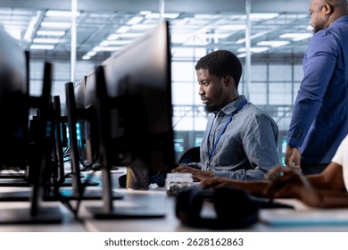 Engineer next to coworkers in server farm checking recovery plan, monitoring data center energy consumption. Employee and colleagues in server room doing routine disk checks