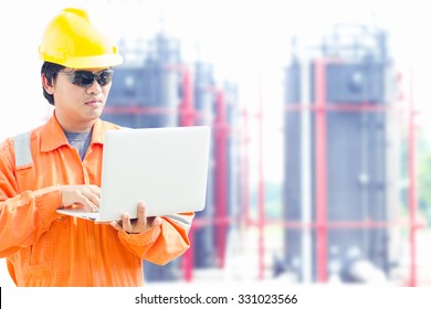 Engineer With A Notebook In An Oilfield. Tank Farm Background