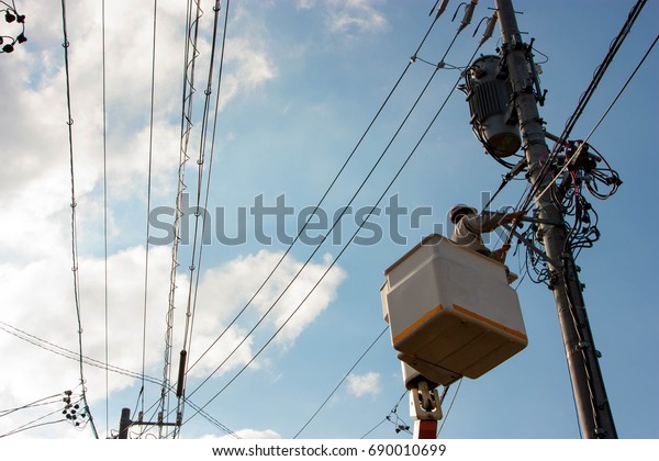 A engineer on cabin car check the electric in\
basket lift blue sky background\
