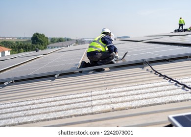 Engineer on rooftop kneeling next to solar panels photo voltaic check laptop for good installation - Shutterstock ID 2242073001