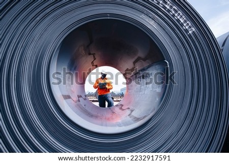 Engineer one worker man inspection on hole rolls of metal carbon steel sheets outside the factory or warehouse.