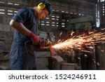 Engineer operating angle grinder hand tools in manufacturing factory - Mechanical engineering student using power tool with hot metal sparks wearing safety equipment - workshop and occupation concept