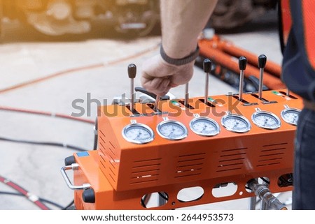 Engineer Operating Hydraulic Control Panel with Levers and Gauges