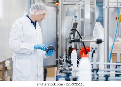 Engineer operator inspecting milk bottles production line dairy factory industry, automatic conveyor for transporting.