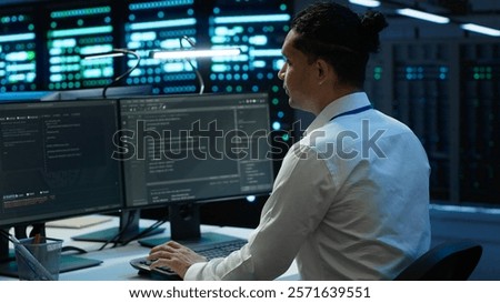 Engineer overseeing data center, making improvements and updates to ensure system can handle networking tasks, handheld camera shot. Indian man in server room tracking network traffic, camera A