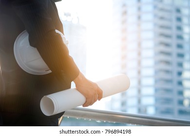 An engineer people is working and controlling the construction which Sky train running through. Engineering holding a plan and Safety Helmets or Head Protection.