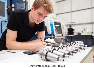 Engineer Planning Project With CNC Machinery In Background
