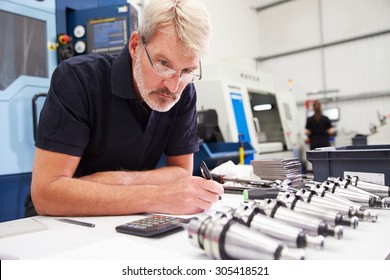 Engineer Planning Project With CNC Machinery In Background