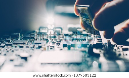 Engineer plugging CPU microprocessor to motherboard socket. Computer technology and hardware maintenance or repair.