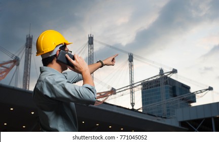 Engineer is pointing the job,Engineer  is setting goal,Engineer is controlling the construction on twilight background,Engineer using a mobile phone to contact the job