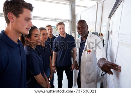 Engineer pointing to whiteboard while training apprentices