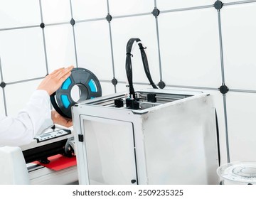 Engineer preparing a 3D printer with filament spool, focusing on the setup process.