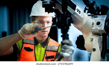 An engineer programs or repairs a high-tech industrial robot. This smart factory uses AI-driven automation for advanced manufacturing or microchip production.