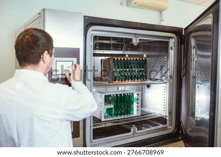 Engineer programs, sets up a test laboratory for finished printed circuit boards. Warm-cold test chamber with printed circuit boards installed during testing.