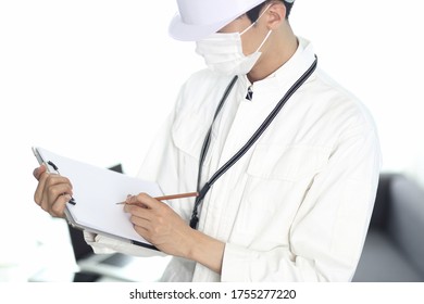 Engineer in protective mask reviewing paperwork in office - Powered by Shutterstock