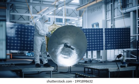 Engineer In Protective Suit Working On Satellite Construction. Aerospace Agency Manufacturing Facility: Scientists Developing Spacecraft For Space Exploration, Communications, Cosmos Observation