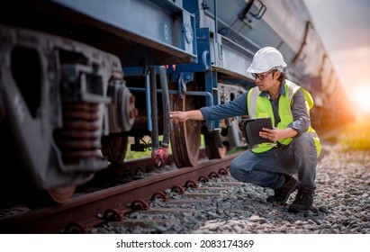 Engineer railway under checking construction process oil cargo train and checking railway work on railroad station with tablet  .Engineer wearing safety uniform and safety helmet in work.