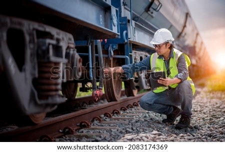 Engineer railway under checking construction process oil cargo train and checking railway work on railroad station with tablet  .Engineer wearing safety uniform and safety helmet in work.