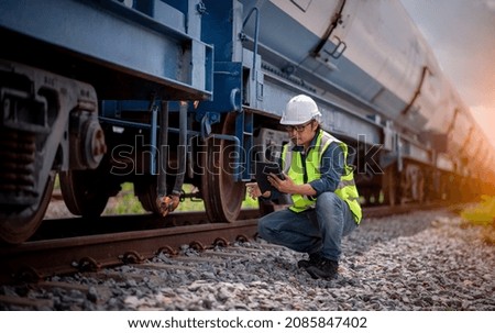 Engineer railway under  checking construction process oil cargo train and checking railway work on railroad station with radio communication .Engineer wearing safety uniform and safety helmet in work.
