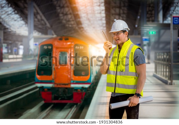 Engineer railway under  checking construction\
process train testing and checking railway work on railroad station\
with radio communication .Engineer wearing safety uniform and\
safety helmet in work.