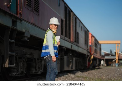 Engineer Railway Under Checking Under The Train On Railroad Station.Engineer Wearing Safety Uniform And Safety Helmet In Work.