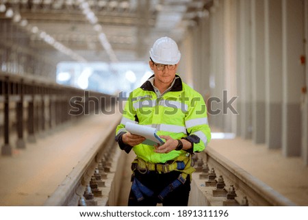 Engineer railway under inspection and checking construction process train work shop and railroad station .Engineer wearing safety uniform and helmet by holding document in work.