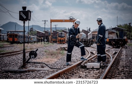 Engineer railway under inspection and checking construction railway switch and maitenence work on railroad station by tablet .Engineer wearing safety uniform and safety helmet in work.