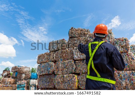 Engineer and Recyclable material. An engineer looking at recycling waste To proceed to the next process. Foreman wearing protective equipments and holding tablet and looking at Recyclable material.