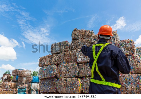 Engineer and Recyclable material. An engineer\
looking at recycling waste To proceed to the next process. Foreman\
wearing protective equipments and holding tablet and looking at\
Recyclable material.