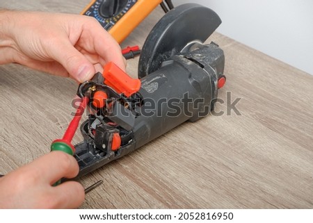 An engineer repairing an angle grinder. Assembling the tool in the process of repair.