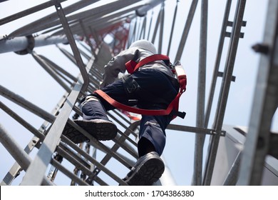 Engineer with safety equipment climb high tower for working telecom communication maintenance.