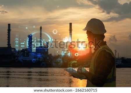 Engineer with safety gear using a tablet to monitor refinery operations enhanced with digital data graphics at sunset. Concept of smart industry and environmental technology.