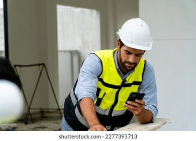 engineer in safety gear wearing hard hat using mobile phone at construction site - Powered by Shutterstock