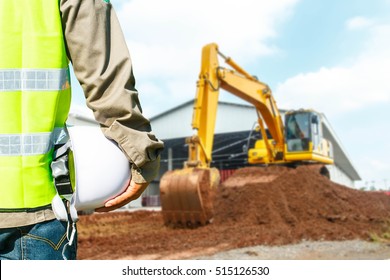 Engineer Or Safety Officer Holding Hard Hat With Excavator Machine At Construction.