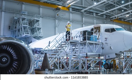 Engineer in Safety Vest Standing next to Airplane in Hangar - Powered by Shutterstock