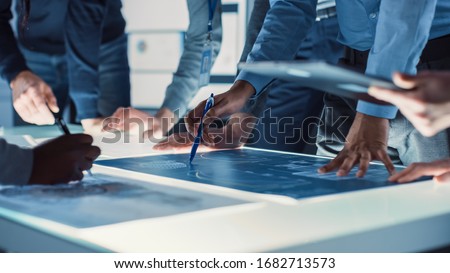 Engineer, Scientists and Developers Gathered Around Illuminated Conference Table in Technology Research Center, Talking, Finding Solution and Analysing Industrial Engine Design. Close-up Hands Shot