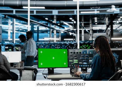 Engineer in server farm using green screen PC to repair equipment storing datasets. IT professional using mockup computer to do debugging on rigs doing computational operations