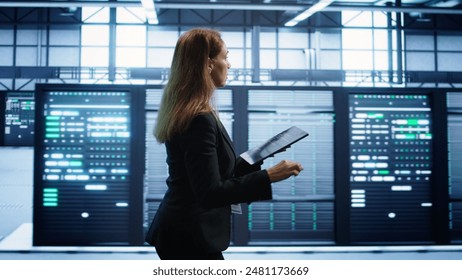 Engineer in server hub checking recovery plan on tablet, monitoring rackmounts energy consumption. Woman in data center making sure rigs are functioning optimally, doing routine disk checks, camera B - Powered by Shutterstock