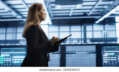 Engineer in server hub checking recovery plan on tablet, monitoring rackmounts energy consumption. Woman in data center making sure rigs are functioning optimally, doing routine disk checks, camera A - Powered by Shutterstock