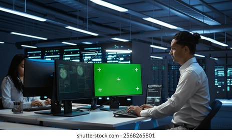 Engineer in server hub using green screen PC to stop hacker passing company firewall and stealing sensitive user data. Worker looking at mockup computer, seeing security breach notification, camera B
