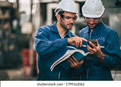 Engineer Service Team Looking At Machine Service Manual Text Book, Working Together As Teamwork In Factory .