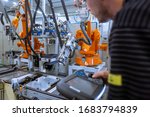 Engineer setting up automatic robot arms in smart factory, automotive industry, industrial concept