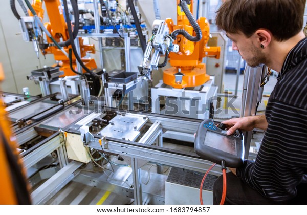 Engineer setting up\
automatic robot arms in smart factory, automotive industry,\
industrial concept
