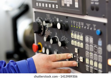 Engineer setup operation parameters of CNC lathe machine using buttons on the control panel. Selective focus.