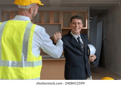 Engineer shaking hands at construction site with happy architect.