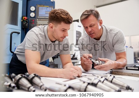 Engineer Showing Apprentice How To Measure CAD Drawings