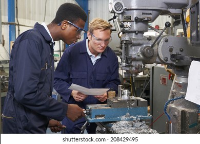 Engineer Showing Apprentice How to Use Drill In Factory - Powered by Shutterstock