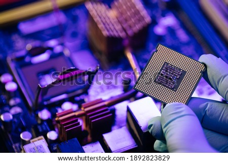 Engineer showing a computer microchip on motherboard background. Electronic circuit board with processor.