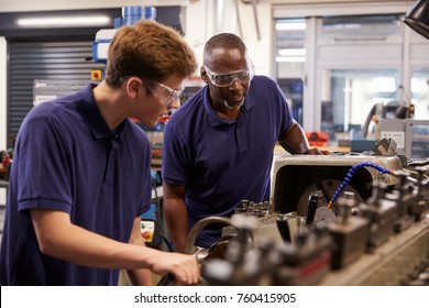 Engineer Showing Teenage Apprentice How To Use Lathe