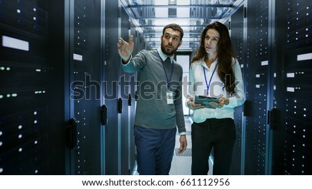 IT Engineer Shows Working Data Center / Server Room to Female Chief Engineer who Holds Tablet Computer.